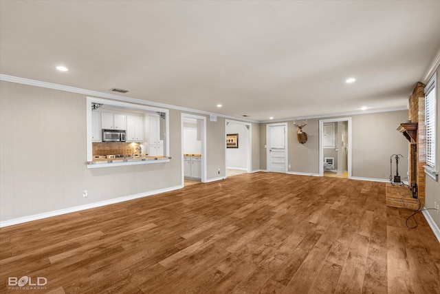 unfurnished living room with crown molding and hardwood / wood-style floors