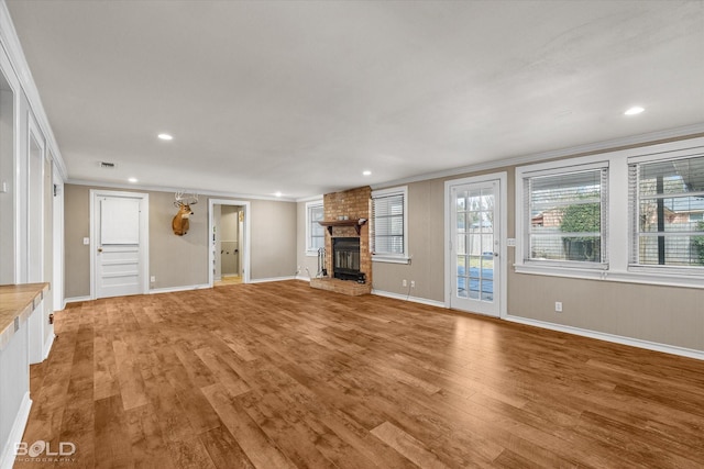 unfurnished living room with hardwood / wood-style flooring, crown molding, and a brick fireplace