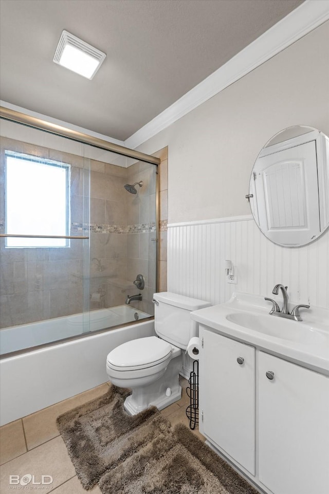 full bathroom with bath / shower combo with glass door, vanity, ornamental molding, tile patterned floors, and toilet