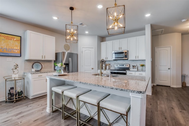 kitchen featuring a center island with sink, sink, white cabinetry, and stainless steel appliances