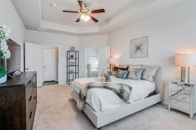 carpeted bedroom featuring ceiling fan and a raised ceiling