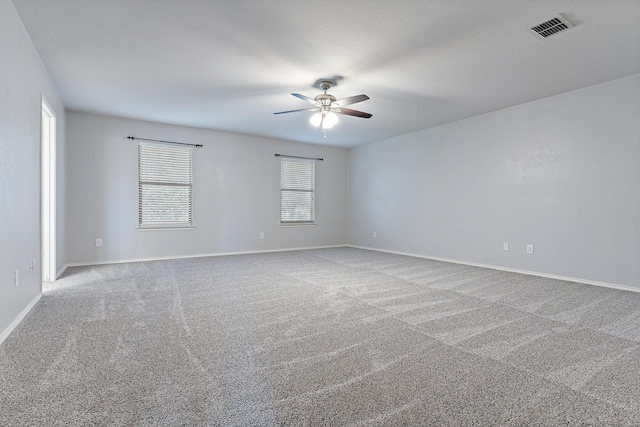 carpeted spare room featuring ceiling fan and plenty of natural light