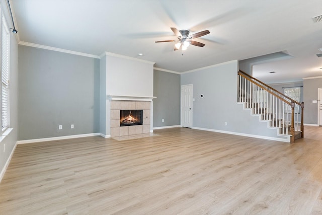 unfurnished living room featuring light hardwood / wood-style floors, ceiling fan, ornamental molding, and a tiled fireplace