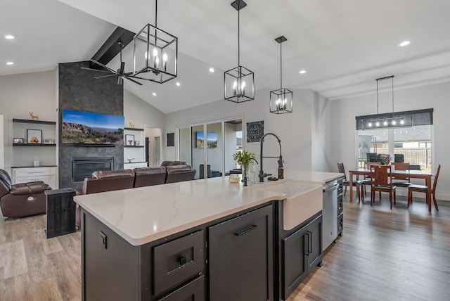 kitchen with a center island with sink, pendant lighting, a fireplace, and light hardwood / wood-style flooring