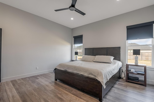 bedroom with hardwood / wood-style flooring, ceiling fan, and multiple windows