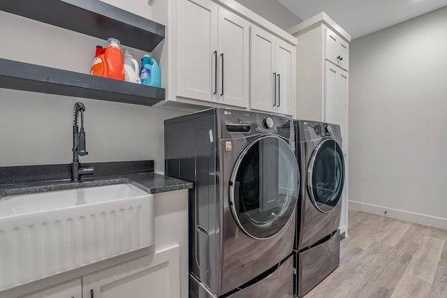 laundry room with sink, cabinets, washing machine and clothes dryer, and light wood-type flooring