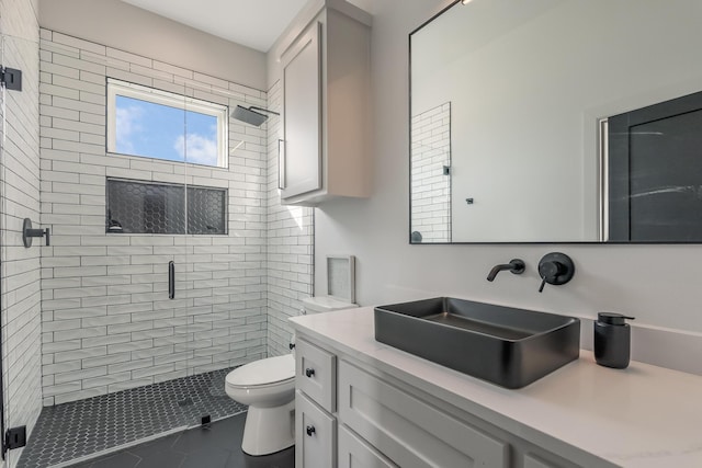 bathroom with tile patterned floors, vanity, a shower with shower door, and toilet