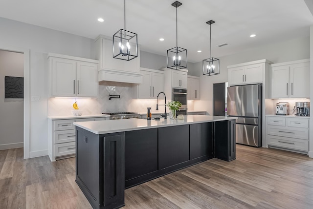 kitchen featuring pendant lighting, a center island with sink, white cabinets, and appliances with stainless steel finishes