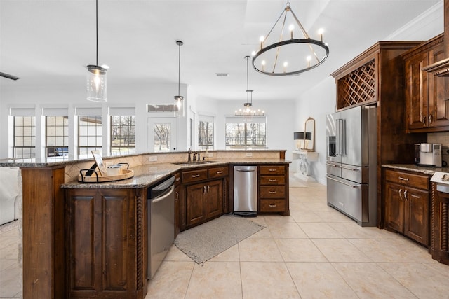 kitchen with dark stone counters, a center island with sink, stainless steel appliances, and decorative light fixtures