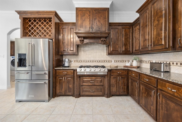 kitchen featuring dark stone countertops, washer / dryer, dark brown cabinets, and stainless steel appliances