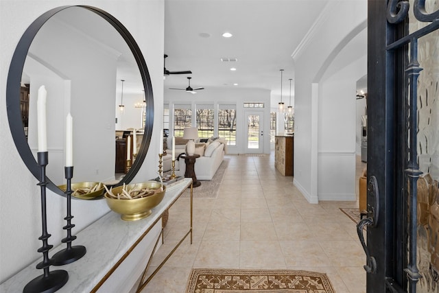 hall with ornamental molding and light tile patterned floors