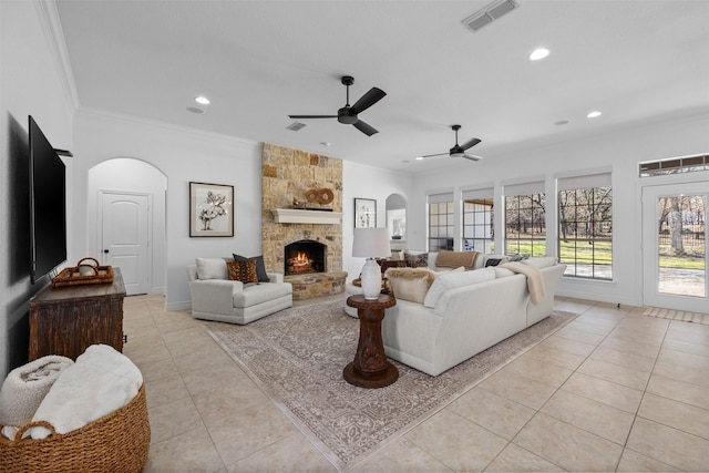 tiled living room with ornamental molding, ceiling fan, and a fireplace