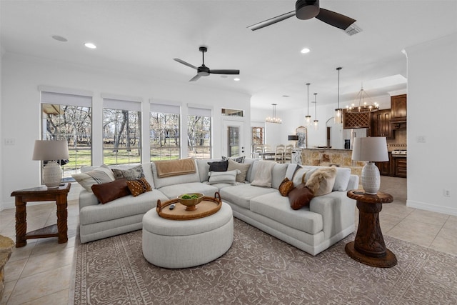 tiled living room featuring ceiling fan with notable chandelier and crown molding