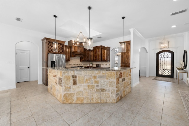 kitchen with stainless steel fridge, pendant lighting, dark stone counters, decorative backsplash, and ornamental molding