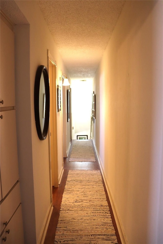 corridor with a textured ceiling and dark hardwood / wood-style flooring