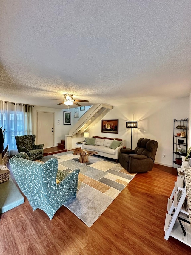 living room featuring ceiling fan, wood-type flooring, and a textured ceiling