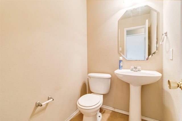 bathroom with toilet, tile patterned flooring, and sink