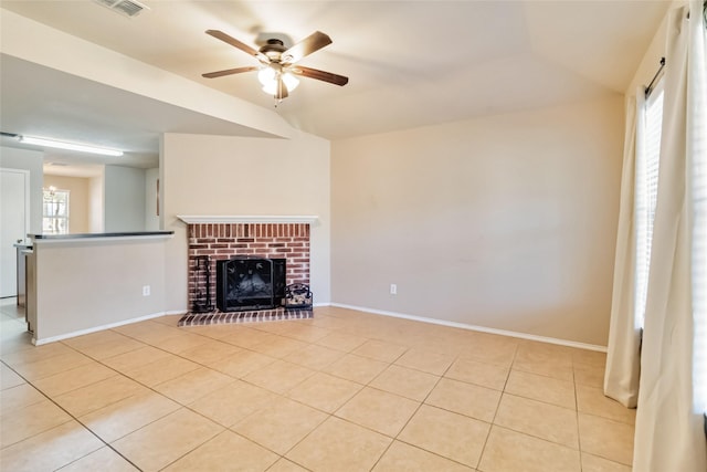 unfurnished living room with a fireplace, ceiling fan, and light tile patterned floors