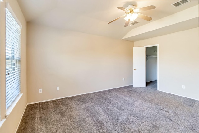 unfurnished bedroom featuring ceiling fan, a closet, lofted ceiling, and dark carpet