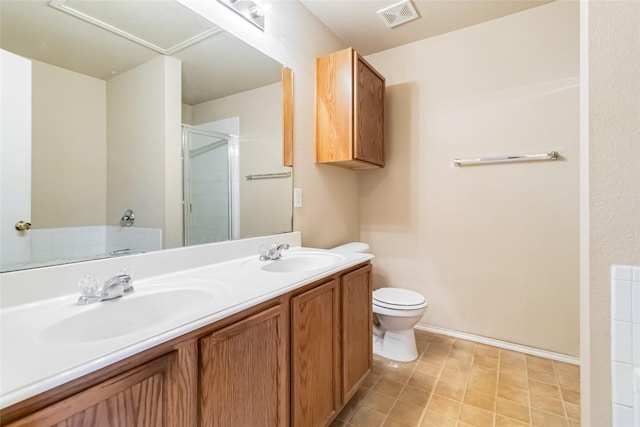 bathroom featuring toilet, vanity, and a shower with shower door