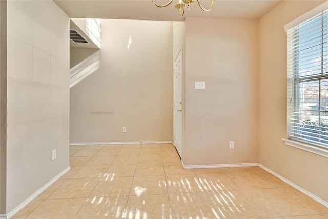 tiled empty room with an inviting chandelier