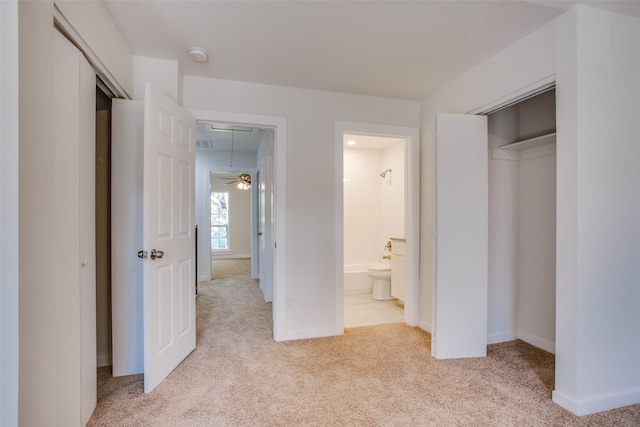 unfurnished bedroom featuring ensuite bathroom, a closet, and light colored carpet