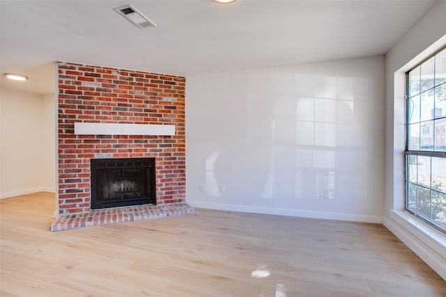 unfurnished living room with plenty of natural light, light hardwood / wood-style flooring, and a brick fireplace