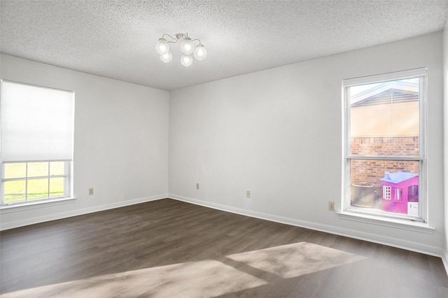 spare room featuring dark hardwood / wood-style flooring, a healthy amount of sunlight, and a textured ceiling