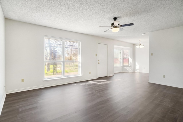 unfurnished living room featuring ceiling fan with notable chandelier, dark hardwood / wood-style floors, a textured ceiling, and a wealth of natural light