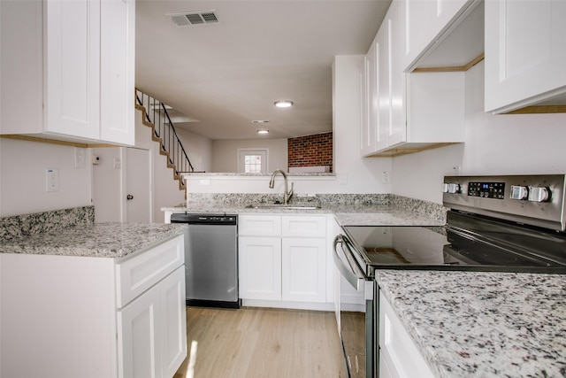 kitchen with light stone countertops, appliances with stainless steel finishes, light wood-type flooring, sink, and white cabinetry