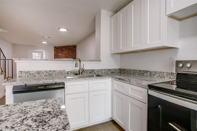 kitchen featuring light stone countertops, sink, kitchen peninsula, white cabinets, and appliances with stainless steel finishes