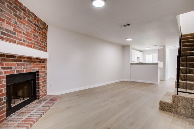 unfurnished living room featuring a fireplace and light hardwood / wood-style floors