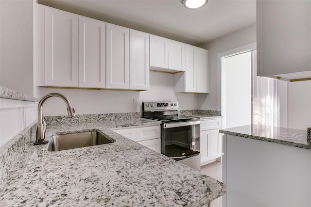 kitchen with light stone counters, sink, white cabinets, and stainless steel range with electric stovetop