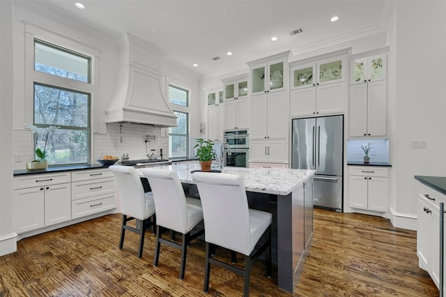 kitchen with dark hardwood / wood-style flooring, tasteful backsplash, stainless steel appliances, dark stone countertops, and a center island