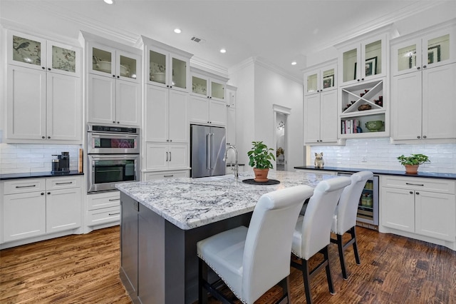 kitchen with white cabinetry, dark stone countertops, a kitchen island with sink, and appliances with stainless steel finishes