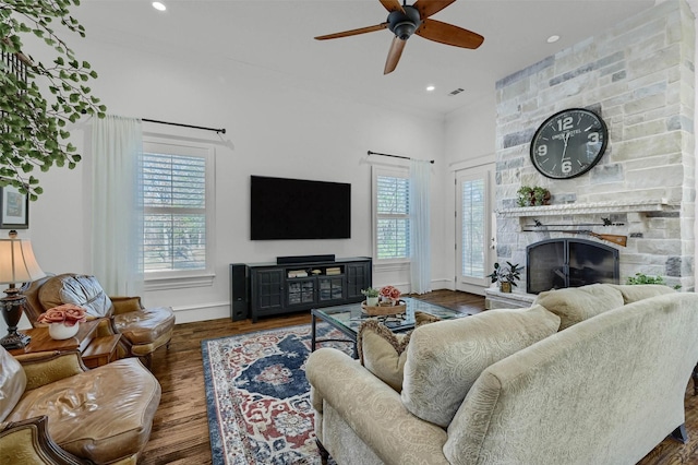 living room featuring a stone fireplace, ceiling fan, and dark hardwood / wood-style flooring