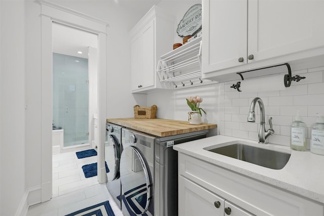 laundry room featuring washer and clothes dryer, light tile patterned flooring, cabinets, and sink