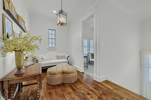 sitting room with hardwood / wood-style flooring, ornamental molding, and a notable chandelier