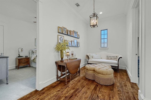 living area featuring a chandelier, crown molding, and dark wood-type flooring