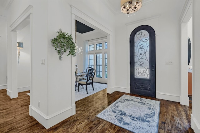 entrance foyer featuring dark hardwood / wood-style floors, ornamental molding, and a chandelier