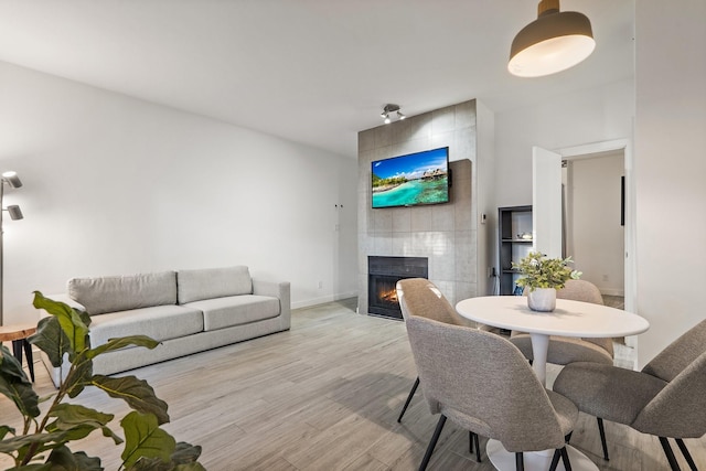 dining room with a tiled fireplace and light hardwood / wood-style floors