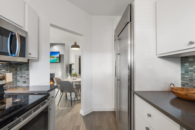 kitchen with white cabinetry, stainless steel appliances, tasteful backsplash, light hardwood / wood-style flooring, and pendant lighting