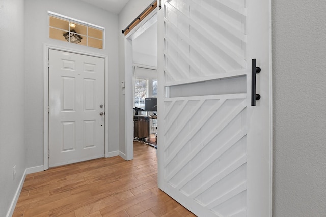 foyer entrance with a barn door and light hardwood / wood-style flooring