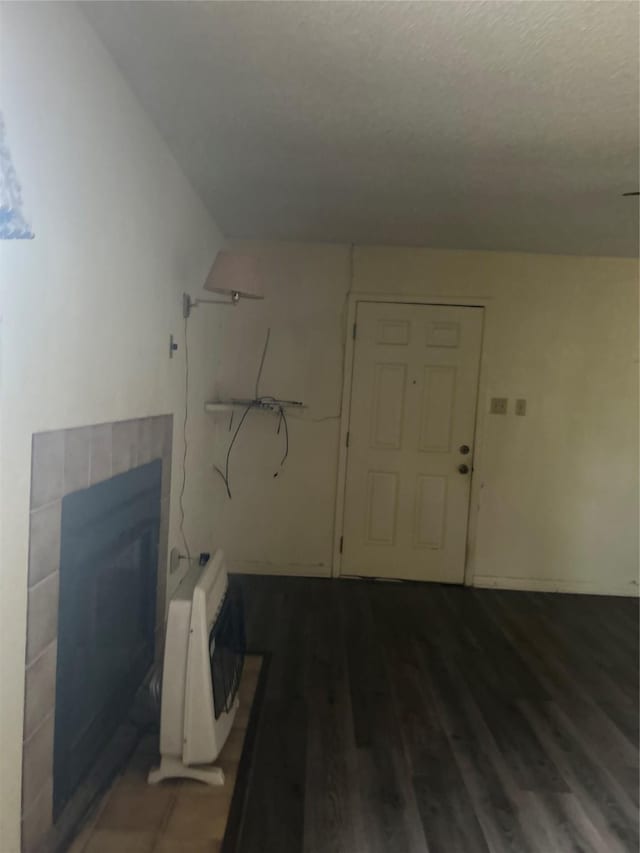 bathroom with a textured ceiling, heating unit, wood-type flooring, and a tile fireplace