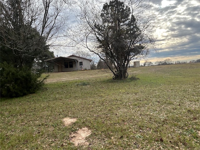 yard at dusk featuring an outbuilding and a rural view