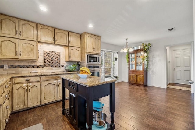 kitchen with pendant lighting, a kitchen island, stainless steel appliances, light stone counters, and a breakfast bar