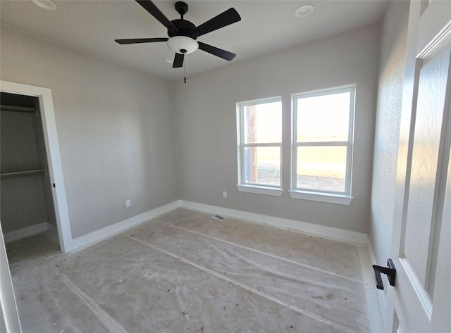 unfurnished bedroom with ceiling fan and a walk in closet