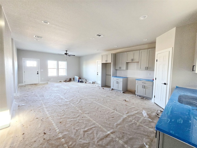 kitchen with a textured ceiling, gray cabinetry, and ceiling fan