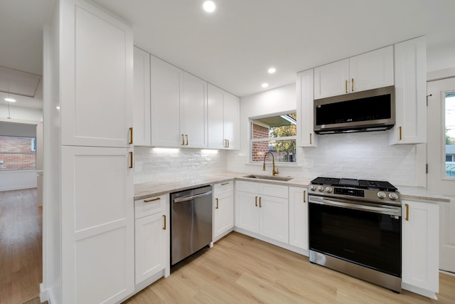 kitchen with light stone countertops, white cabinetry, sink, and stainless steel appliances