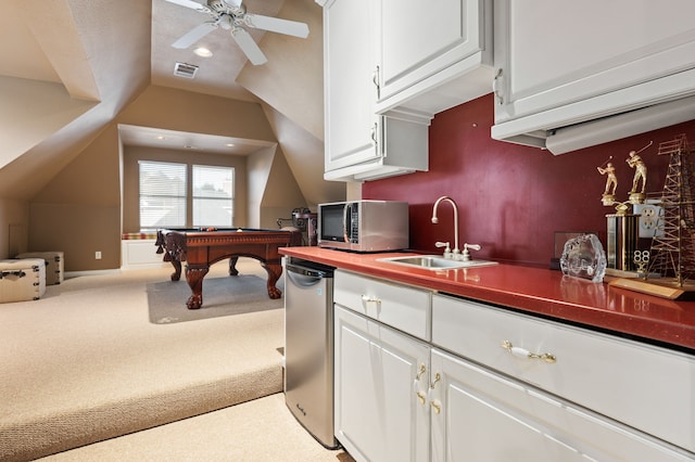 kitchen with vaulted ceiling, sink, white cabinets, light colored carpet, and stainless steel appliances